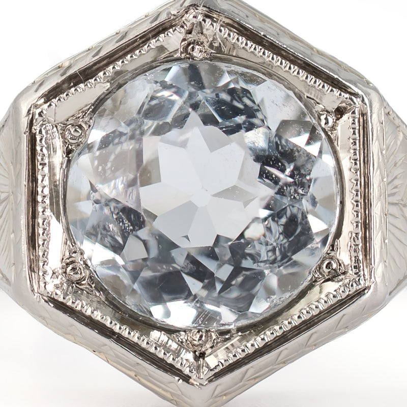 Extreme macro top view of a period-correct native-cut 1.30-carat round aquamarine showing cutting facets and icy blue color.
