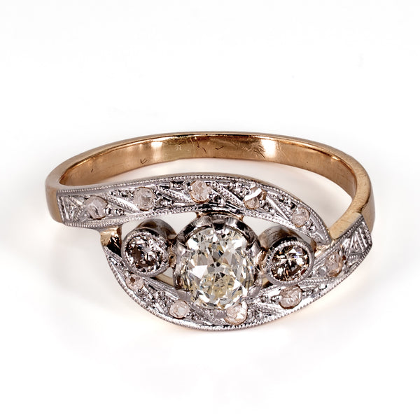 Elevated front view of an antique bypass ring highlighting the warm tone of the center old mine-cut diamond and accent stone detailing.