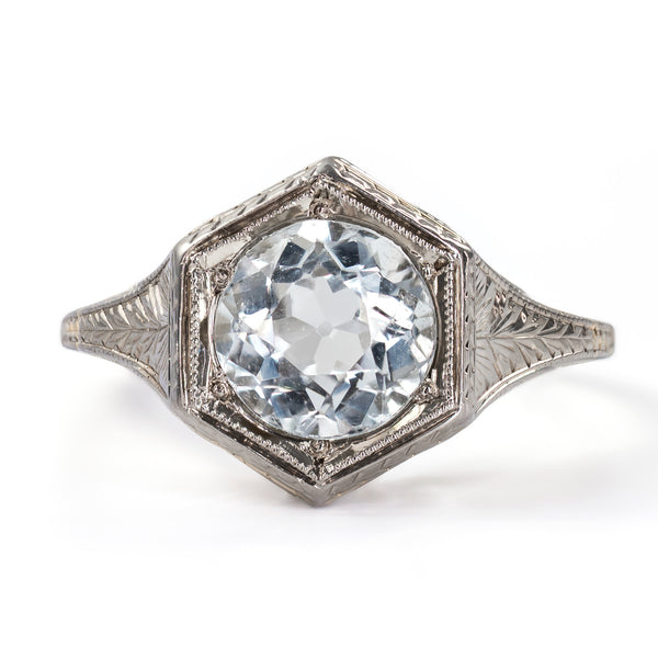 Straight-on face-up view displaying the symmetry of a round aquamarine centered in a crisp Art Deco hexagonal frame.