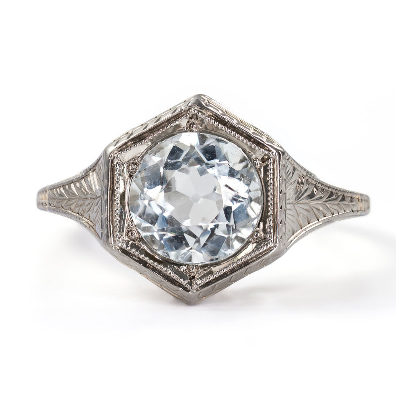 Straight-on face-up view displaying the symmetry of a round aquamarine centered in a crisp Art Deco hexagonal frame.