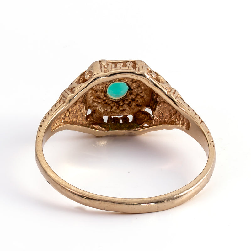 Underside view of the 14K gold ring setting showing the open under-bezel beneath the round green emerald and interior band construction.
