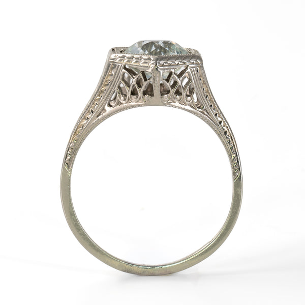 Upright perspective view showing the carved foliate shoulder, geometric openwork gallery, and hexagonal setting of the 18K white gold Art Deco Belais ring.
